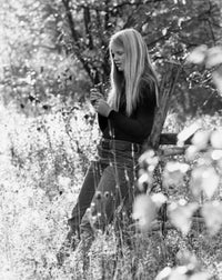 Poster of a teenage girl leaning against a wooden post in a meadow, showcasing serenity and youth.