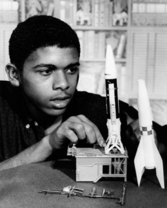 Teenage boy assembling plastic rocket model poster print showcasing creativity.