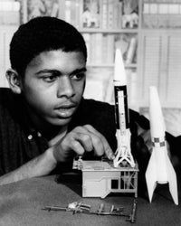 Teenage boy assembling plastic rocket model poster print showcasing creativity.