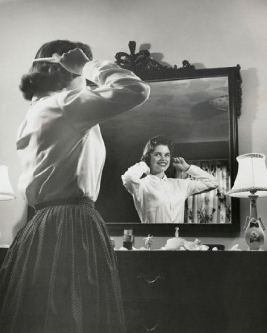 Side profile of a teenage girl combing her hair in front of a mirror poster print.
