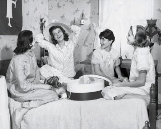 Poster print of four teenage girls sitting on a bed together, capturing a moment of friendship.