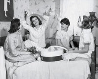 Poster print of four teenage girls sitting on a bed together, capturing a moment of friendship.