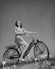 Low angle view poster print of a teenage girl sitting on a bicycle.