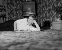 Daydreaming young woman laying on carpet poster print.