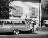 Parents and children loading luggage into a car poster print
