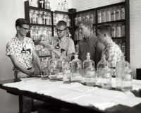 Poster of four boys conducting a chemistry experiment in a laboratory.