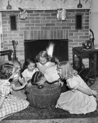 High angle view of a boy bobbing for apples with girls around him.
