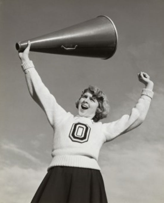 Low angle view of a female cheerleader holding a megaphone and shouting.