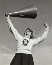 Low angle view of a female cheerleader holding a megaphone and shouting.