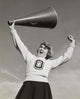 Low angle view of a female cheerleader holding a megaphone and shouting.