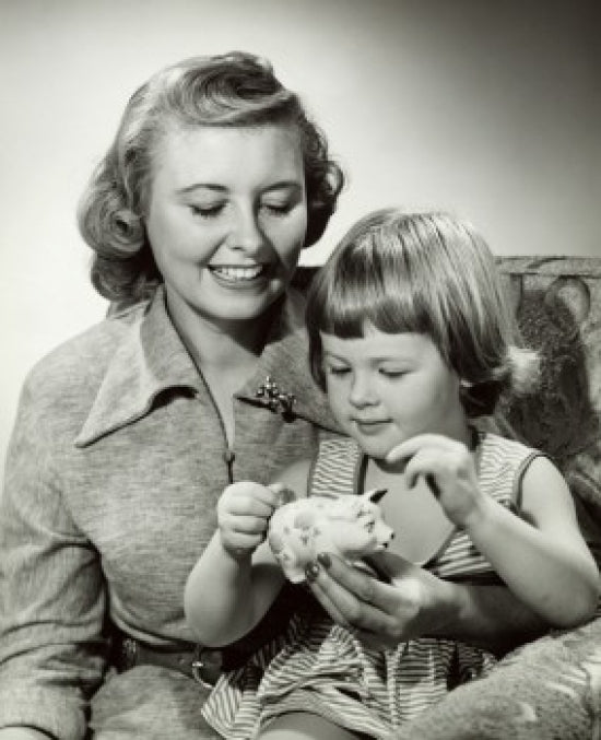 Close-up of a mother watching her daughter putting a coin into a piggy bank poster print
