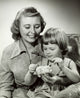 Close-up of a mother watching her daughter putting a coin into a piggy bank poster print
