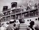Group of people standing near a departing cruise ship poster print.