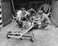 Side profile of a boy and his father working on a model car poster print