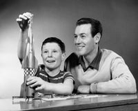 Boy playing with a model rocket with his father poster print.