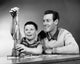 Boy playing with a model rocket with his father poster print.