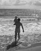 Rear view of a father carrying his son on the beach poster print.