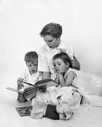 Mid adult woman reading a story book to her children poster print.