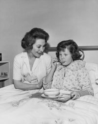 Poster Print of a girl eating food with a nurse beside her.