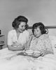 Poster Print of a girl eating food with a nurse beside her.