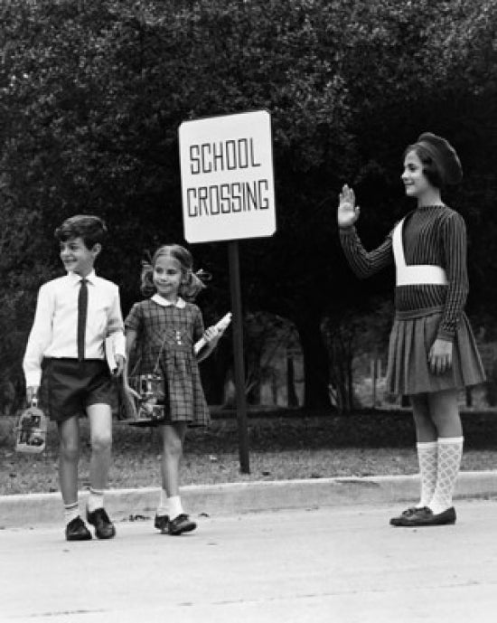 Female crossing guard assisting children at road crossing poster print