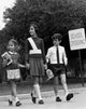 Poster print of a female crossing guard helping children at a road crossing.