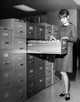 Businesswoman searching for files in a filing cabinet poster print