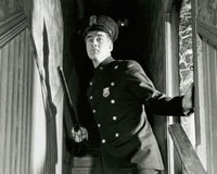 Policeman holding a nightstick and standing on staircase poster print.