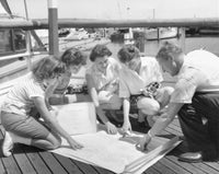 Parents and children looking at a map on a pier poster print