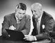 Close-up of two businessmen reading a file poster print.