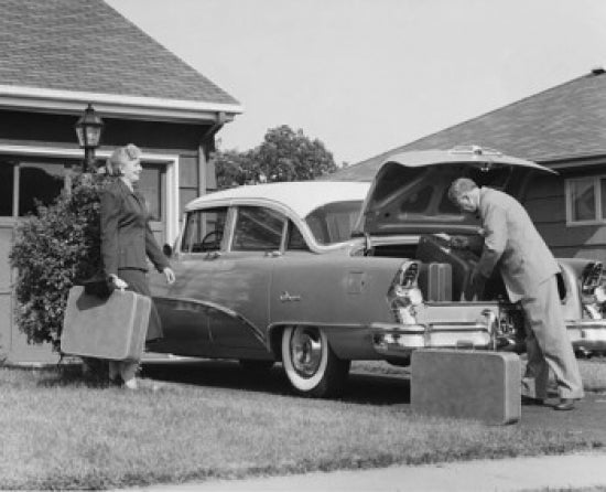 Poster print of a senior couple loading luggage into a car trunk.