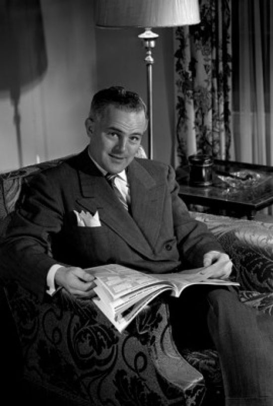 Portrait of a mature man sitting in an armchair reading comics - Poster Print.