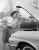 Young woman inspecting a car engine poster print