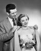 Close-up poster print of a young man putting an overcoat on a young woman.