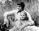 Young couple resting in a field poster print showcasing serenity and romance.