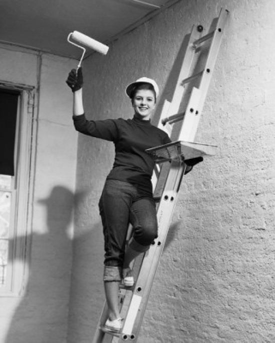 Portrait of a Young Woman holding a paint roller on a ladder.