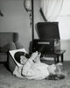 Teenage girl lying on carpet holding records poster print.