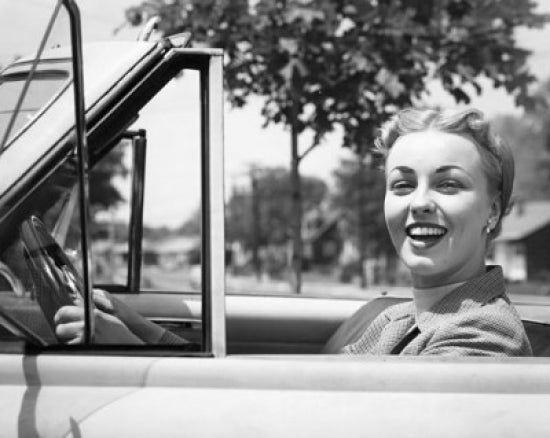Close-up view of a young woman smiling while sitting in a car.