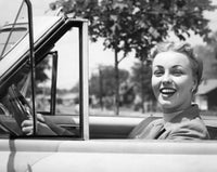 Close-up view of a young woman smiling while sitting in a car.