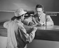 Man standing in front of a bank teller poster print.