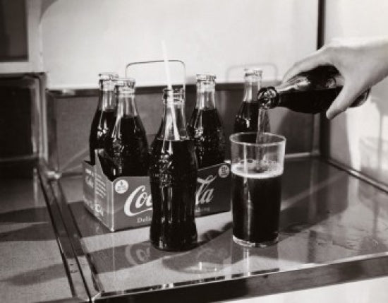 Close-up of a person's hand pouring soda into a glass poster print.