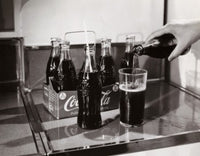 Close-up of a person's hand pouring soda into a glass poster print.