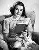 Poster of a mid adult woman reading a book with a cat on her lap