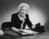 Businesswoman sitting at desk looking at a calendar poster print.