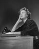 Poster print of businesswoman thinking at desk in office setting.