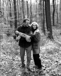 Mature couple in forest holding firewood, serene nature poster print.