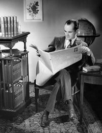 Mid adult man sitting in a chair reading a newspaper poster print.