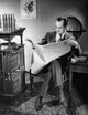 Mid adult man sitting in a chair reading a newspaper poster print.