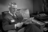 Man reading magazine in chair poster print
