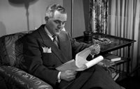 Man Reading Report in Chair Poster Print - A thoughtful image perfect for home or office decor.